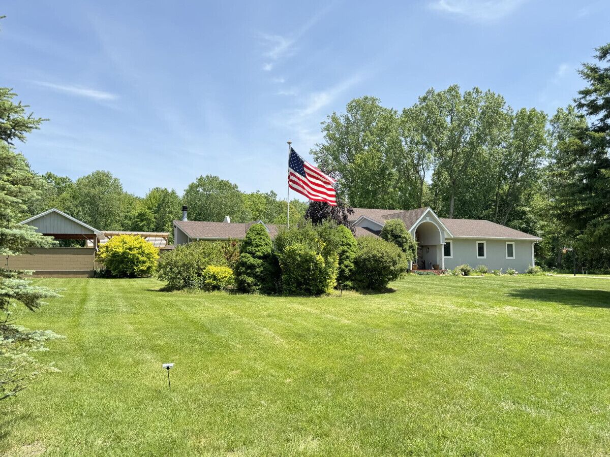 A residential area with a well-maintained lawn, a house with a porch, and an American flag.