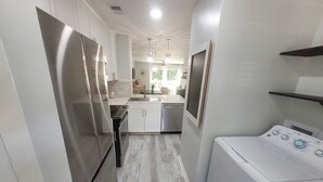 A compact kitchen with stainless steel appliances, a built-in oven, and a washing machine.
