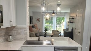 A modern kitchen with white cabinetry, a built-in dishwasher, and a large island with a sink.