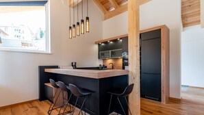 A modern kitchen with a central island, bar stools, and a built-in refrigerator.