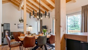 A spacious dining area with a wooden ceiling and a large window.