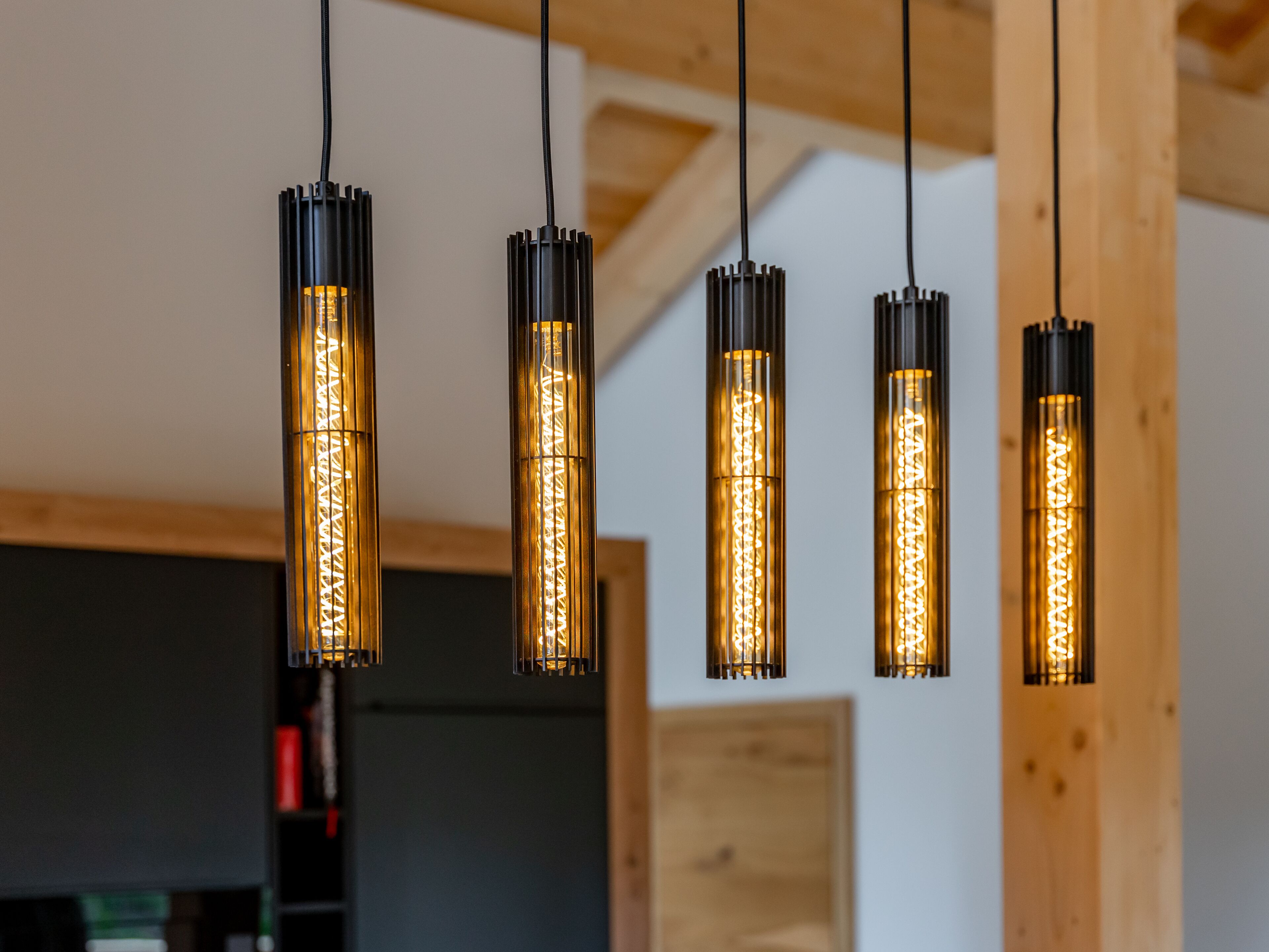 A series of pendant lights with a warm glow, hanging from a ceiling with exposed wooden beams.