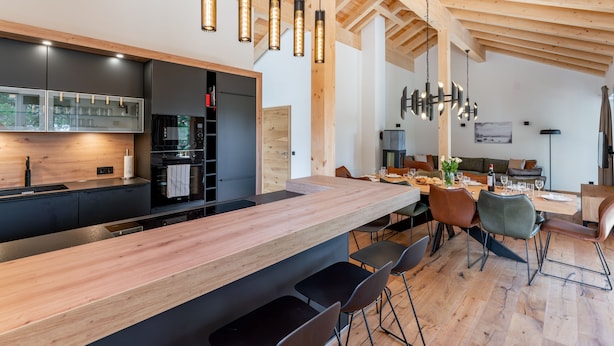 A modern kitchen with a wooden countertop, black cabinets, and pendant lights.