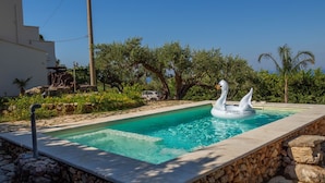 A swimming pool with a swan float, surrounded by stone walls and greenery. - Villa Marianninswimming pool with hot tub in private garden (Castellammare del Golfo)