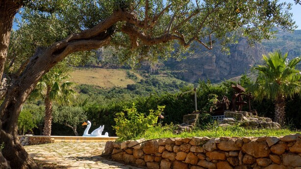 A stone pathway leading to a statue of swans, surrounded by greenery and a stone wall. - Villa Marianninswimming pool with hot tub in private garden (Castellammare del Golfo)