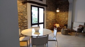 A dining area with a round table and chairs, a stone wall, and a window with a view. - Villa Marianninswimming pool with hot tub in private garden (Castellammare del Golfo)
