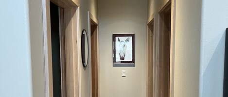 A hallway with wooden flooring, beige walls, and a framed picture on the wall.