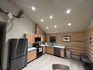 A modern kitchen with wooden cabinets, stainless steel appliances, and a mounted deer skull. - Clear creek cabin (Seward)