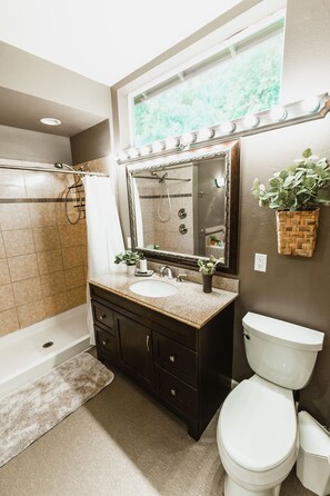 A bathroom with a vanity, two sinks, a mirror, a shower, and a toilet. - Hot tub! Retreat for large or small groups. Sleeps 16! View Auoras and Denali! (Eagle River)
