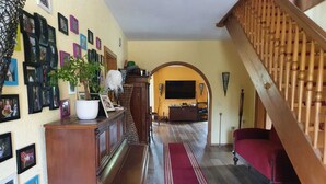 A living room with a wooden staircase, a red sofa, a piano, and a wall decorated with framed photos. - House in Teichland Pool, sauna, fireplace on the Cottbus Baltic Sea with proximity to the Spreewald (Teichland)