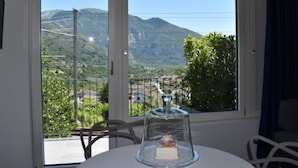 Une pièce dotée d’une grande fenêtre donnant sur les montagnes, d’une table ornée d’un centre de table en forme de dôme de verre et d’une chaise.