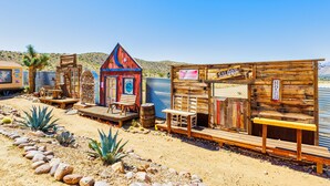Un bâtiment rustique en bois, avec une enseigne indiquant « Saloon » et une autre indiquant « Budweiser ».