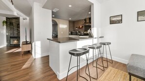 Une cuisine moderne dotée d’un îlot central, de tabourets de bar et d’une cheminée.