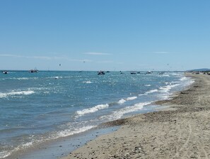 Ein Strand mit Booten, Menschen im Wasser und sandigem Ufer.