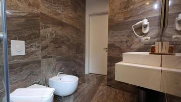 Un baño moderno con bidé, inodoro y tocador con espejo.