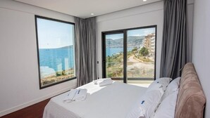 Habitación de hotel con una cama grande, vistas al mar y un balcón.