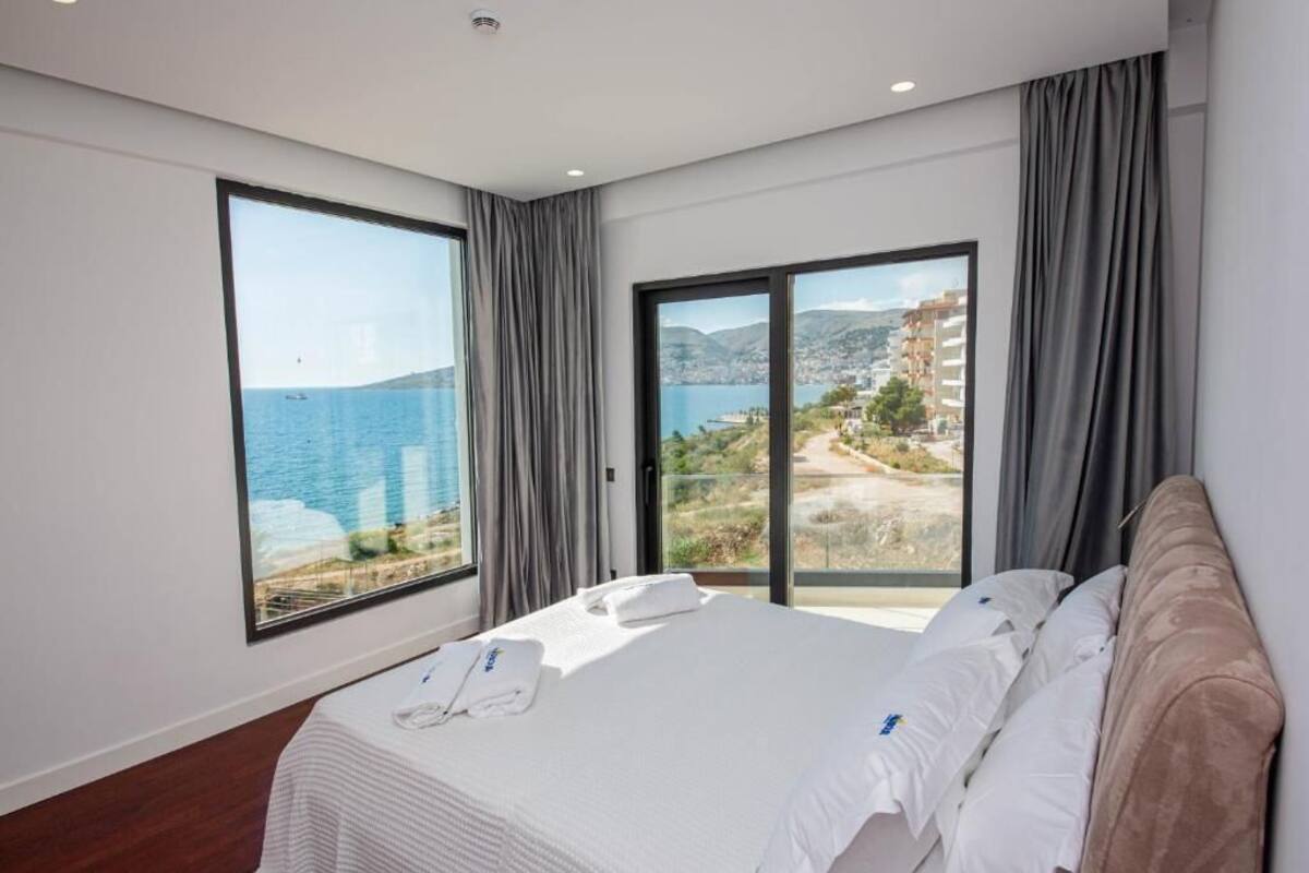 A hotel room with a large bed, a view of the sea, and a balcony.