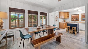 A spacious kitchen with wooden cabinets, a central island with stools, and large windows with blinds. - Adorable Laguna Beach Cottage with Pool, 1-Minute Walk to the Beach (Panama City Beach)