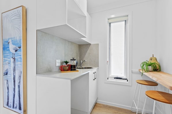 Una cocina moderna con armarios blancos, cafetera y ventana.