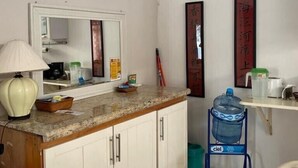 A compact kitchen with a marble countertop, a white cabinet, a water dispenser, and a mirror above the sink. - Romantic Zone 5 Blocks From the Beach (Puerto Vallarta)