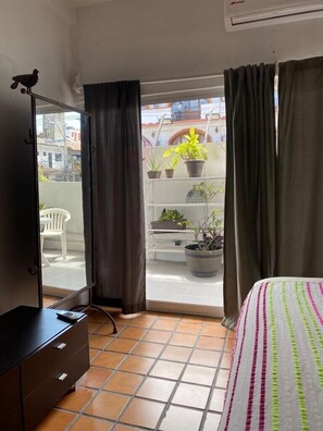 A bedroom with a bed, a dresser, and a balcony with potted plants. - Romantic Zone 5 Blocks From the Beach (Puerto Vallarta)