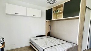 Ein gemütliches Schlafzimmer mit Bett, Einbauschrank und einer kleinen Ablage mit Pflanzen.