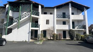 Ein mehrstöckiges Gebäude mit weißer Fassade, grünen Geländern und einem roten Ziegeldach.