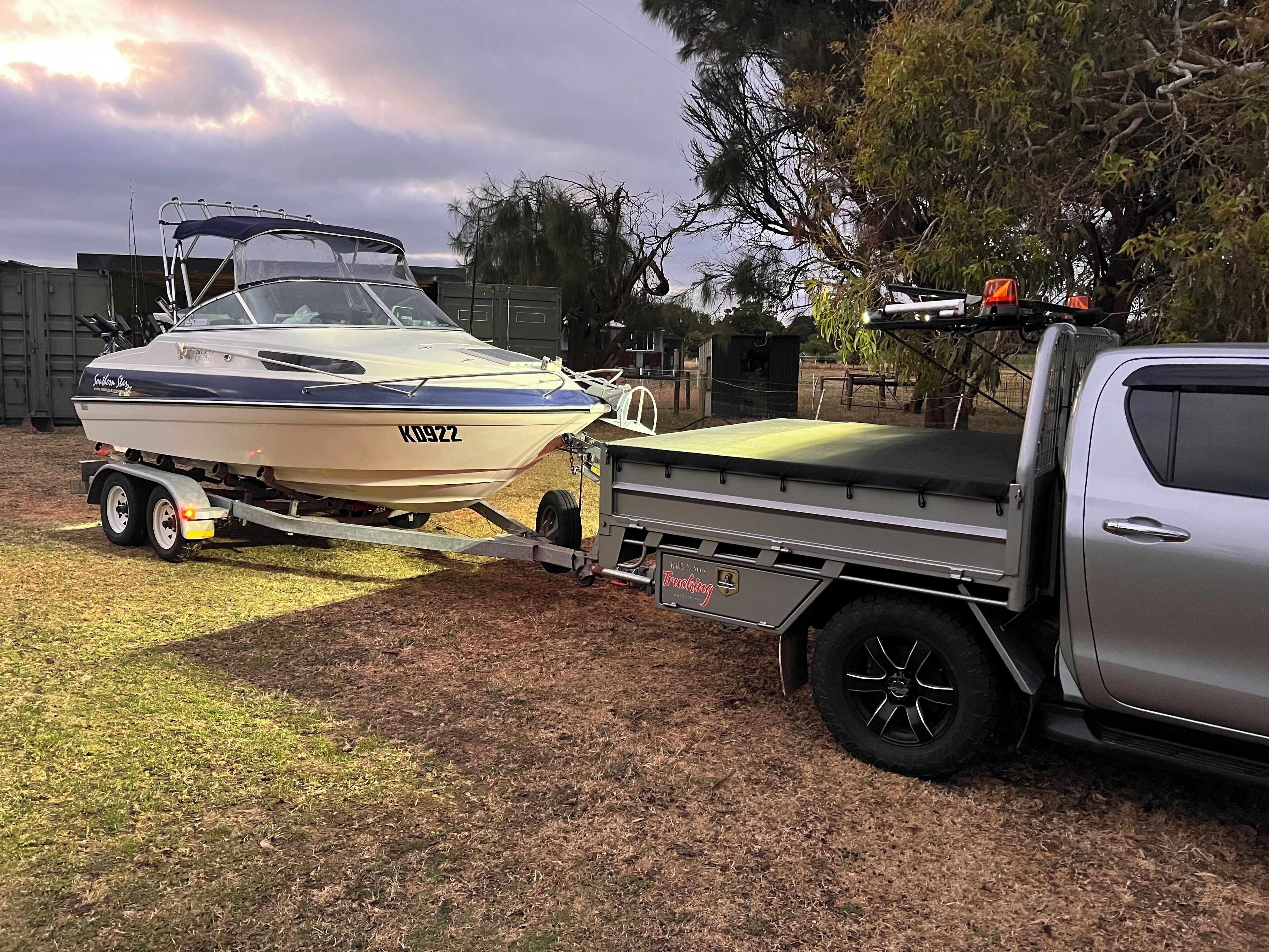 A boat on a trailer attached to a pickup truck.