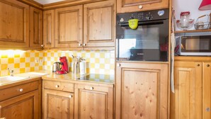 A kitchen with wooden cabinets, a Bosch oven, a microwave, and a checkered backsplash. - Spacious bright apartment at the slopes with parking (La Rosière)