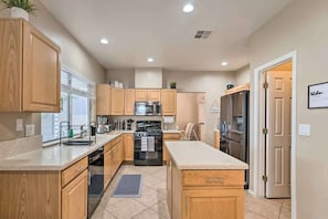 A modern kitchen with wooden cabinets, stainless steel appliances, and a central island.