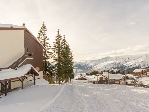 A snow-covered ski resort with buildings, a ski lift, and a mountain backdrop.