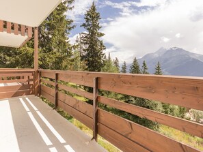 A wooden balcony with a view of a mountain range.