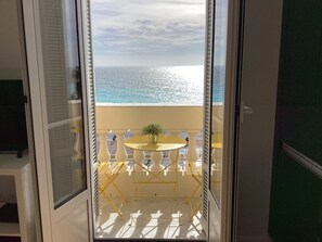 A balcony with a table and chairs, a potted plant, and a view of the ocean. - Nice, Promenade des Anglais Avec vue Imprenable (Nice)