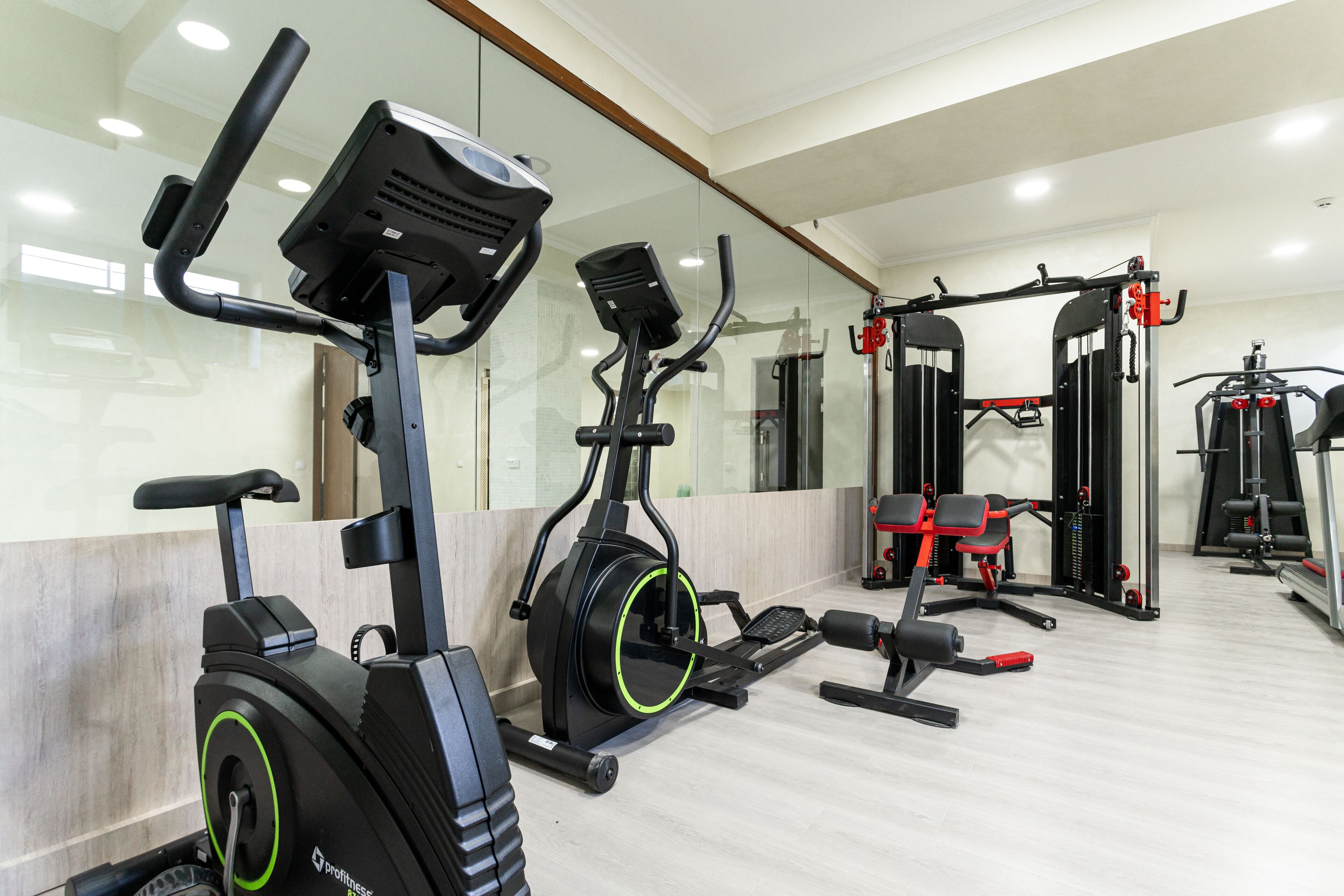 A gym with stationary bikes, a bench press, and a squat rack.