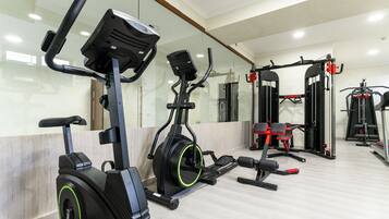 A gym with stationary bikes, a bench press, and a squat rack.