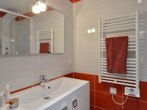 Une salle de bain moderne avec un lavabo blanc, un miroir et un porte-serviettes sur lequel est posée une serviette rouge.