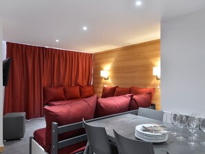 Une pièce moderne comprenant un canapé, une table à manger, des chaises et un téléviseur.