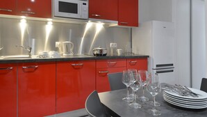 Et moderne køkken med røde skabe, en mikrobølgeovn og et spiseområde med et bord dækket til fire personer.