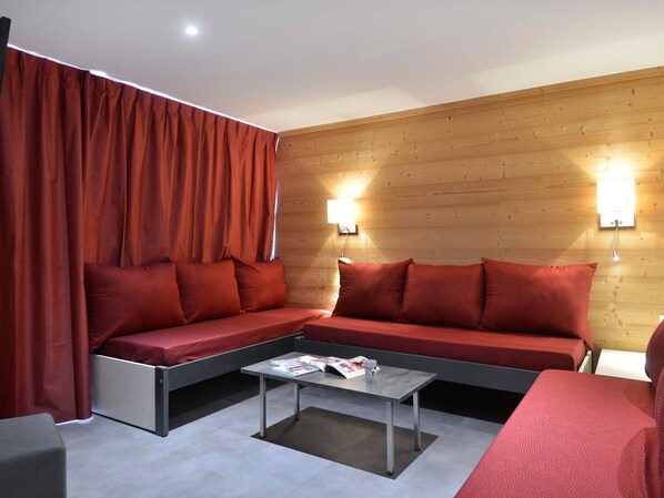 Un salon moderne avec un canapé, une table basse et un rideau rouge.