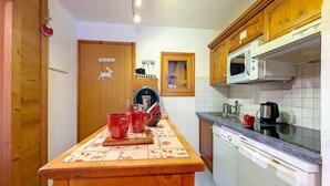 A kitchen with wooden cabinets, a microwave, a sink, and a coffee maker. - Bright Spacious Apartment · Near Slopes · Balcony · Free Wi-Fi (Saint-Martin-de-Belleville)