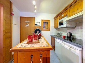 Une cuisine avec des meubles de rangement en bois, un four à micro-ondes, un évier et une machine à café.