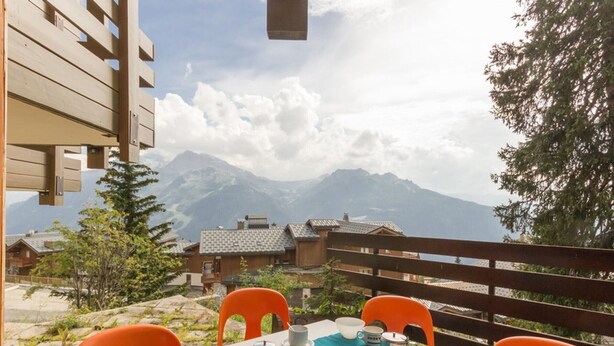 Area pranzo all'aperto con tavolo imbandito per due, sedie e vista sulle montagne.