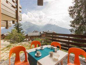 An outdoor dining area with a table set for two, chairs, and a view of mountains in the background. - Bright studio with balcony near slopes (La Rosière)