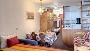 Una stanza compatta con un tavolo da pranzo, sedie, un divano e un letto a castello.