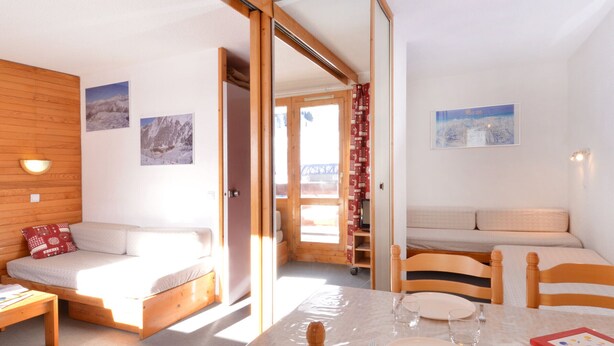 A cozy room with a bed, a sofa, a dining table, and a wooden ceiling. - Bright studio near slopes with balcony - Pets allowed (Plagne Bellecôte)