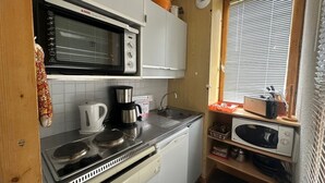 A compact kitchen with a stove, kettle, coffee maker, microwave, and a window with blinds. - Bright studio near slopes with balcony - Pets allowed (Plagne Bellecôte)