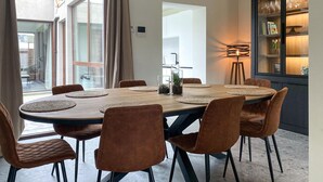 Un coin repas avec une table ronde, six chaises et une lampe moderne.