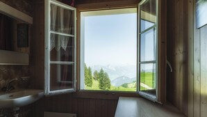 Un baño con paredes de madera, un lavamanos y una ventana con vistas a la montaña.