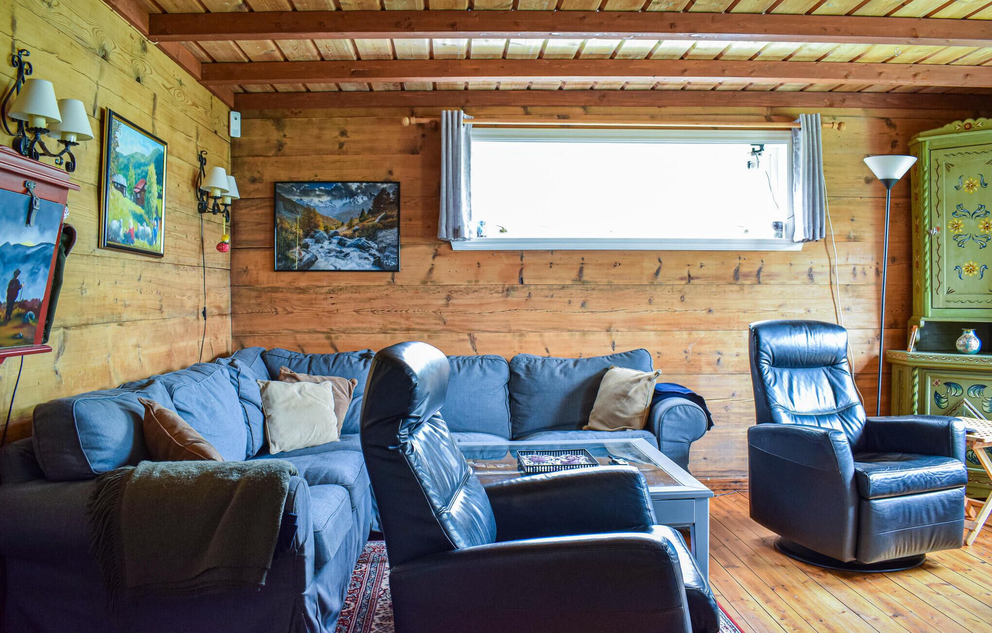 A cozy living room with a wooden interior, a large window, and a leather sofa.