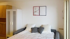 Une chambre à coucher avec un lit, une armoire et deux tableaux encadrés accrochés au mur.
